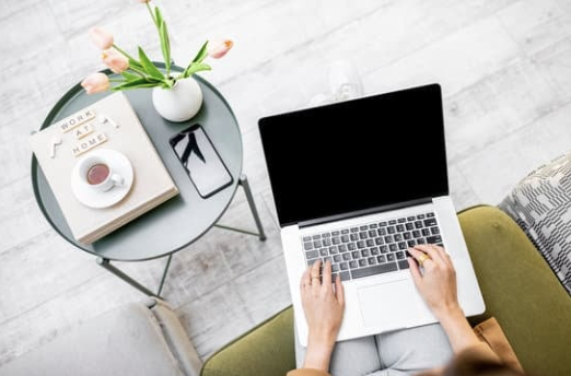 laptop next to a table with tea and a notebook